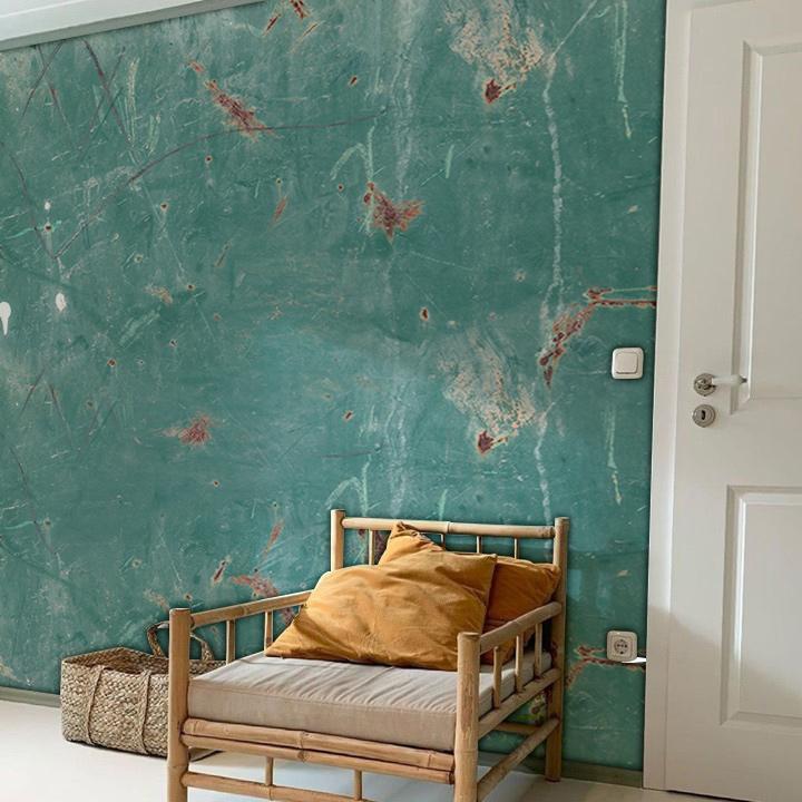 Teal vintage wallpaper in a rustic chic room with bamboo chair, neutral flooring, and white door.