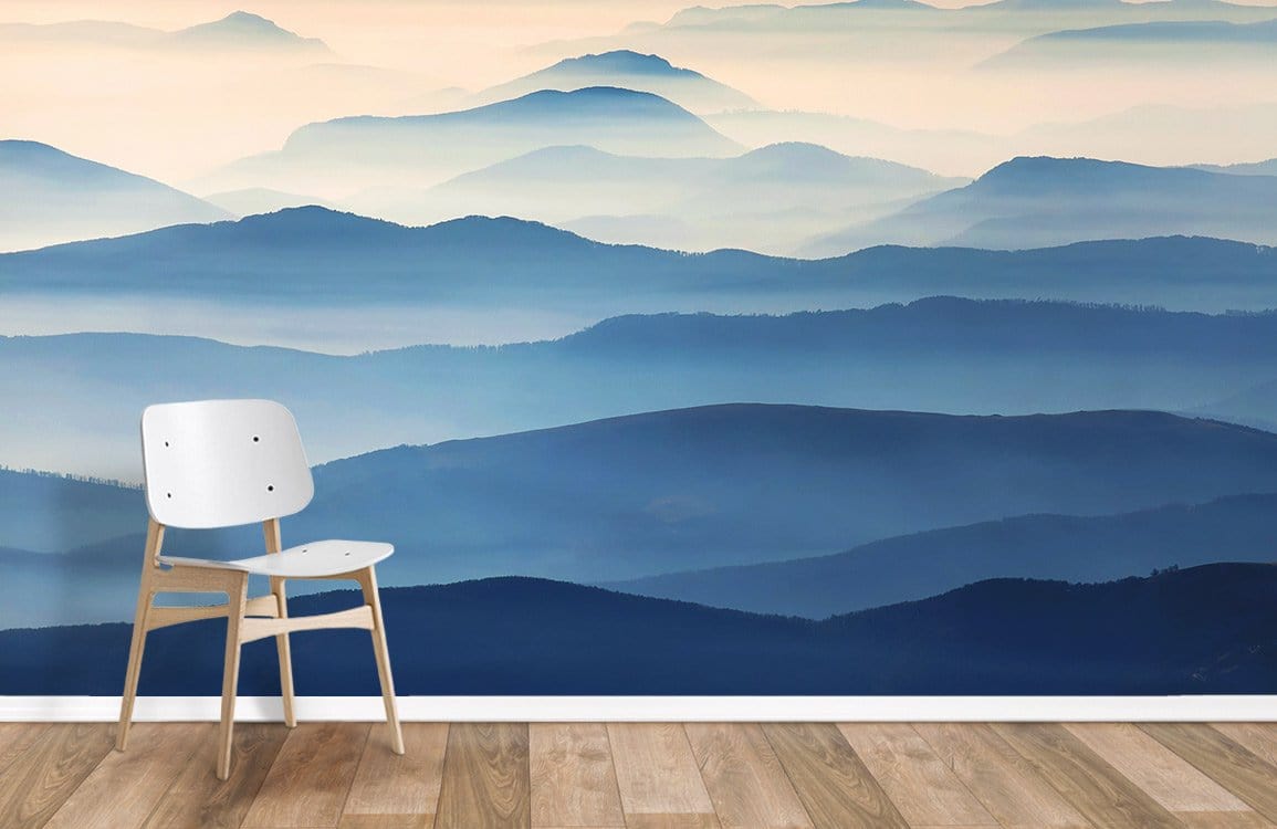Misty Blue Mountain Landscape Mural Wallpaper in living room with wooden flooring and modern white chair.