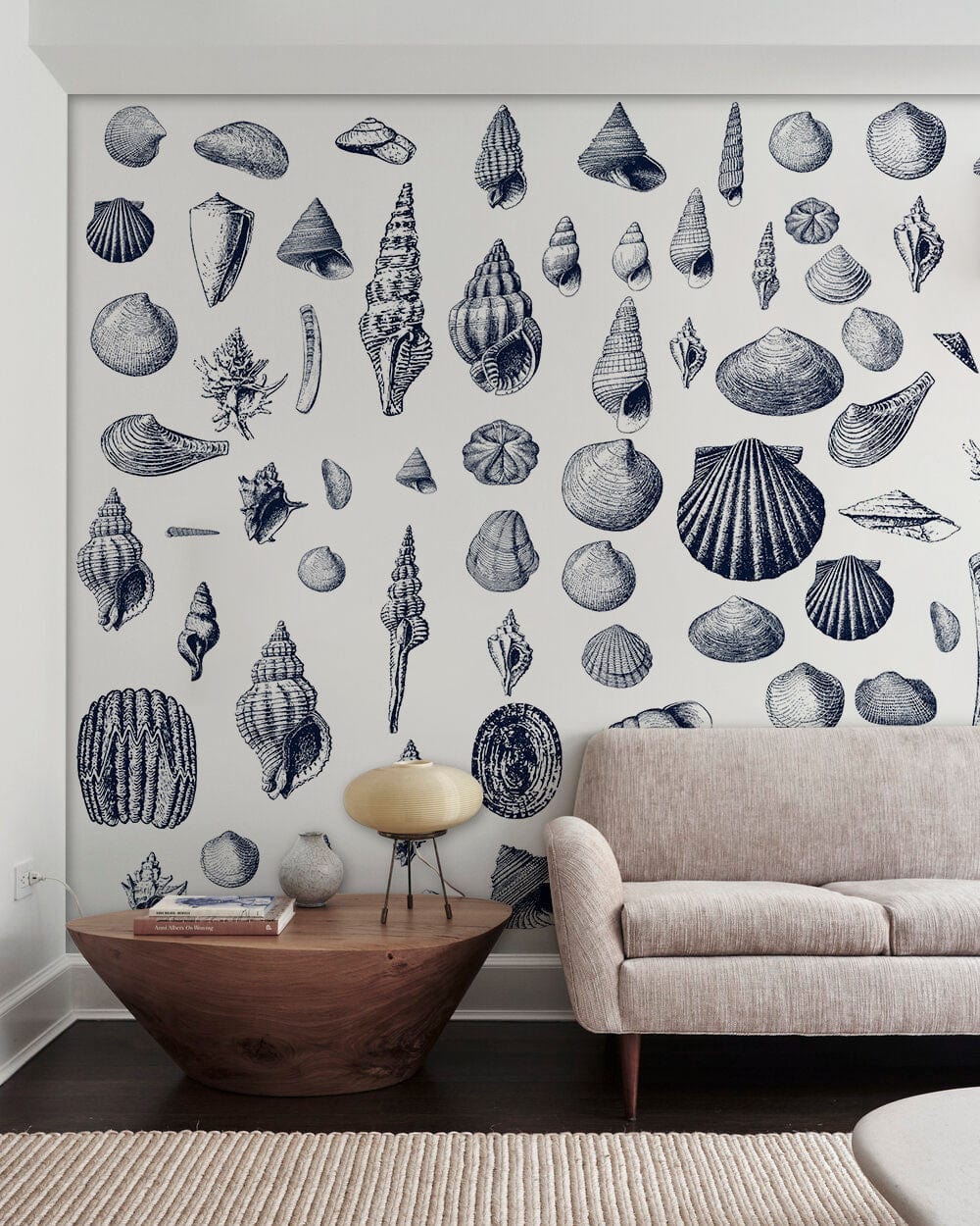 Nautical blue seashell wallpaper in coastal design with beige sofa and wooden coffee table.