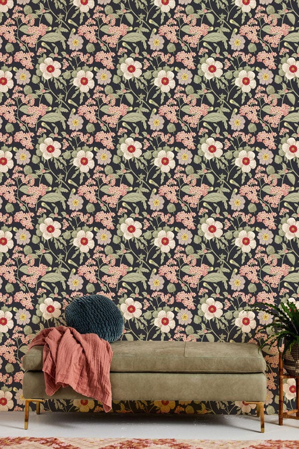 Vintage floral wallpaper in soft pink and green tones behind olive-green sofa in stylish room.