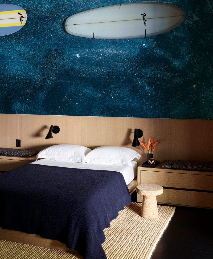 Midnight Ocean Blue Abstract Textured Wallpaper in modern bedroom with surfboard, wooden bed, woven rug.