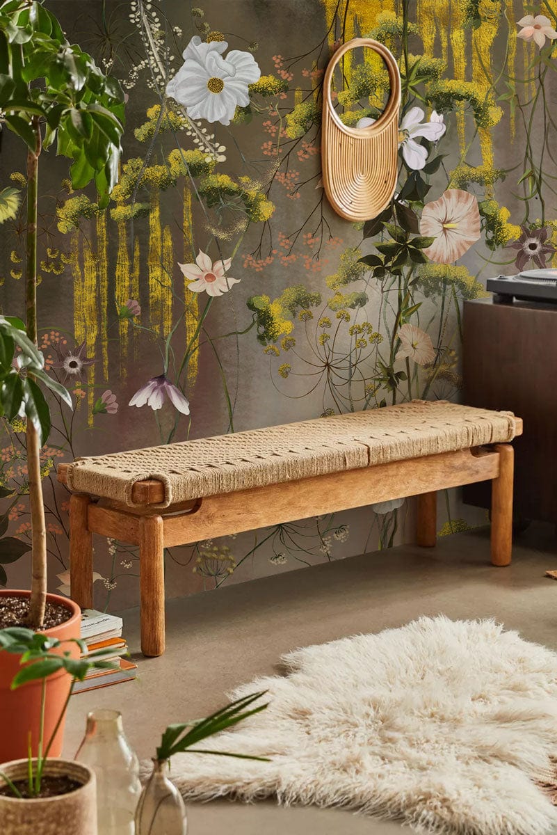 Whimsical floral mural wallpaper in vintage style with wooden bench, shaggy rug, and circular mirror.