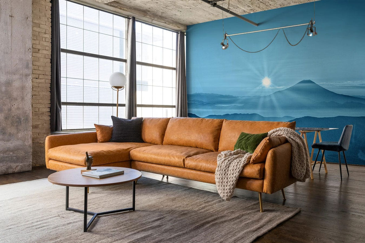 Serene mountain mural wallpaper in living room with brown sofa, wood flooring, and industrial decor.