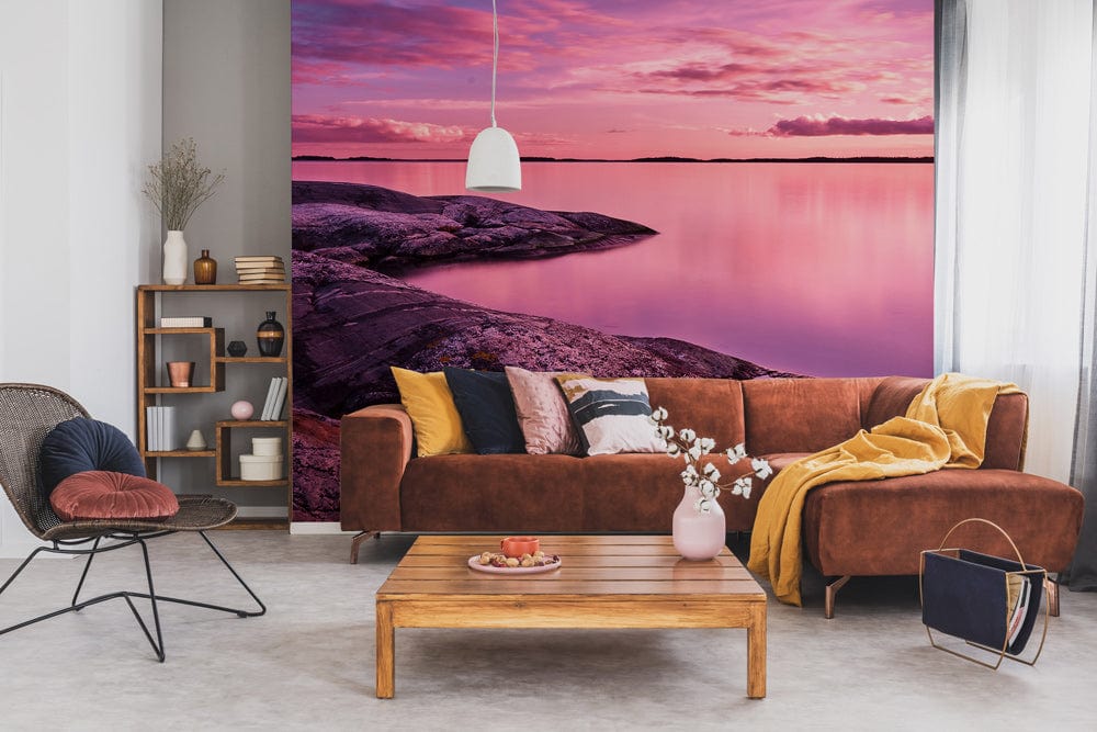 Serene Pink Sunset Lake Mural: Brown sofa, modern shelving, grey flooring, cosy lounge ambience.
