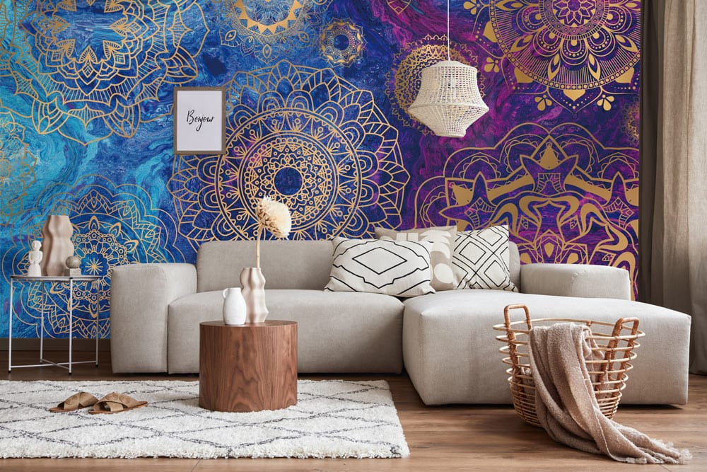 Elegant Mandala Pattern Wallpaper in gold, blue, and purple hues adorns living room with beige sofa.