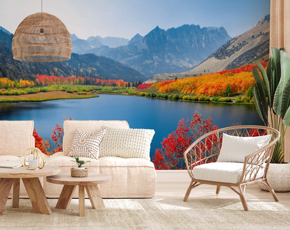 Vibrant mural wallpaper with autumn mountains; wicker furniture, cream sofa, neutral decor in living room.