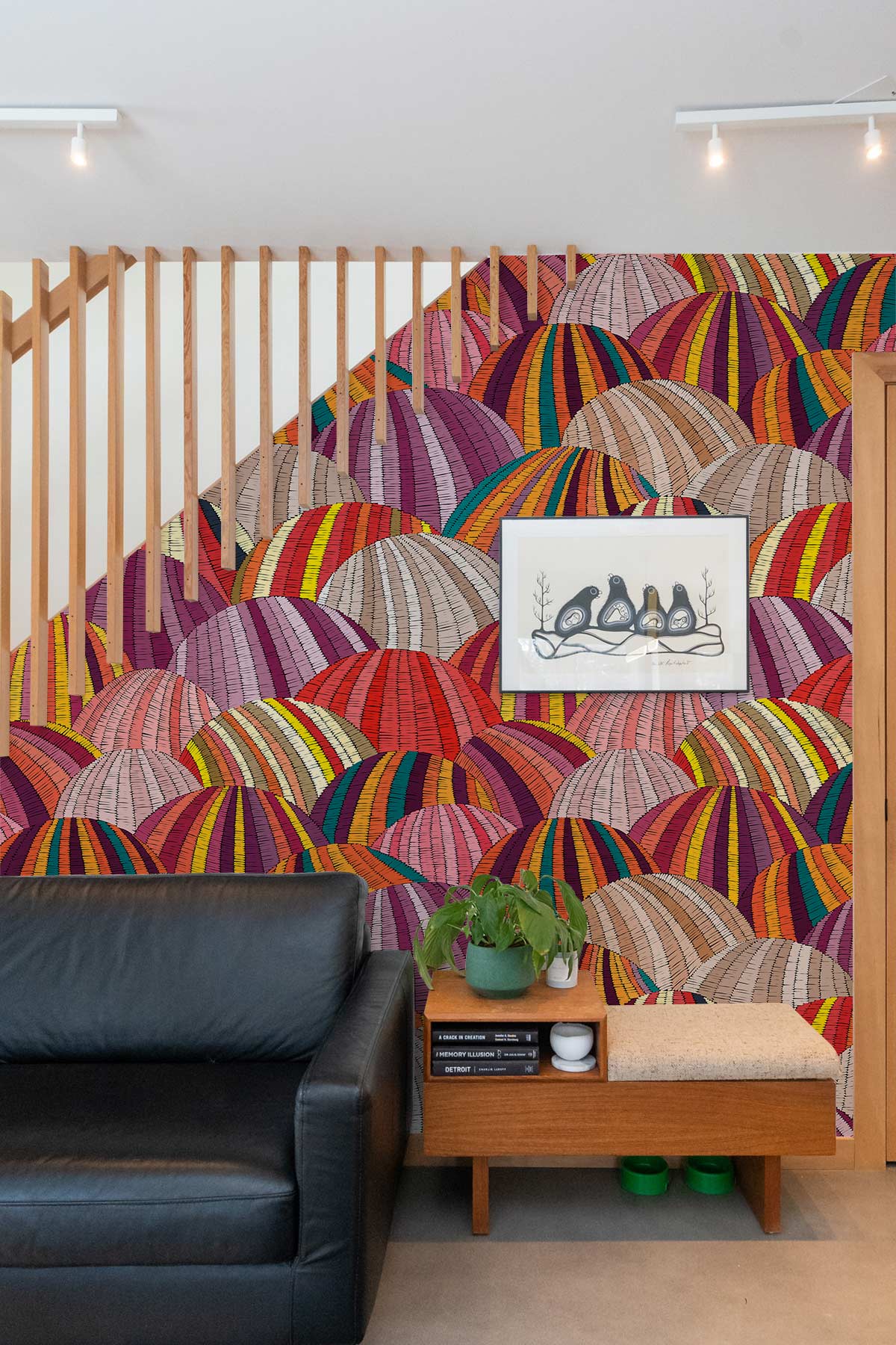 Vibrant geometric wallpaper, black leather sofa, wooden sideboard, modern living room with wall art.