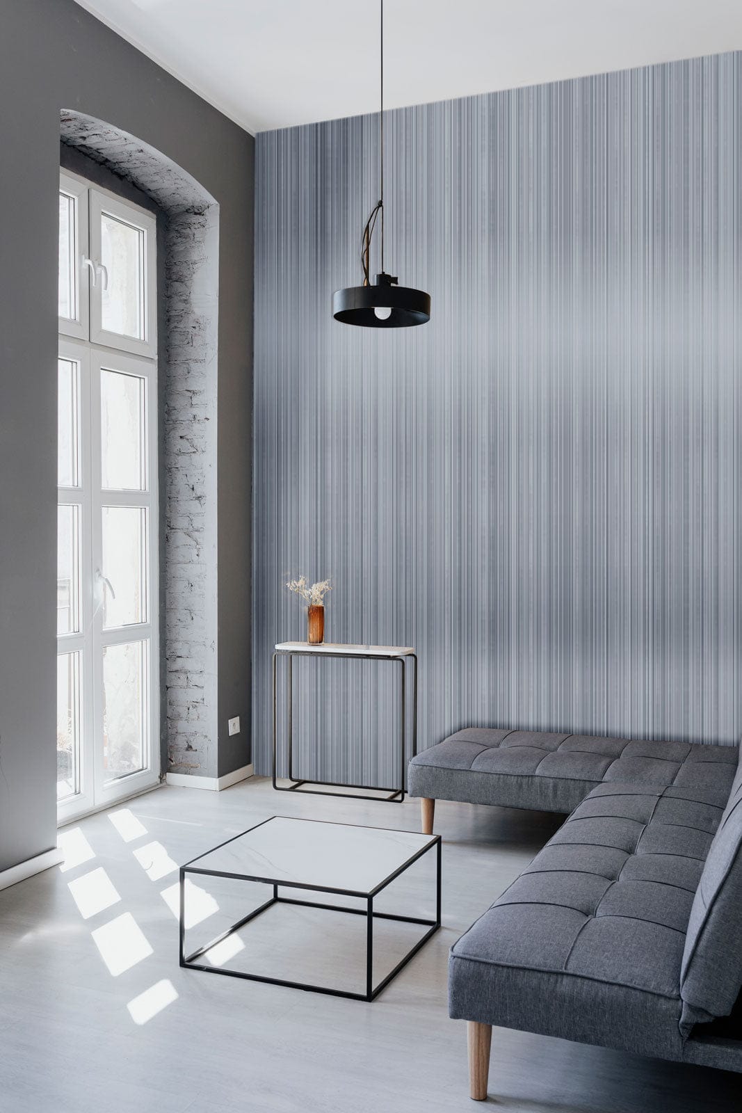 Elegant grey striped wallpaper in modern living room with grey sofa, black table, and light flooring.