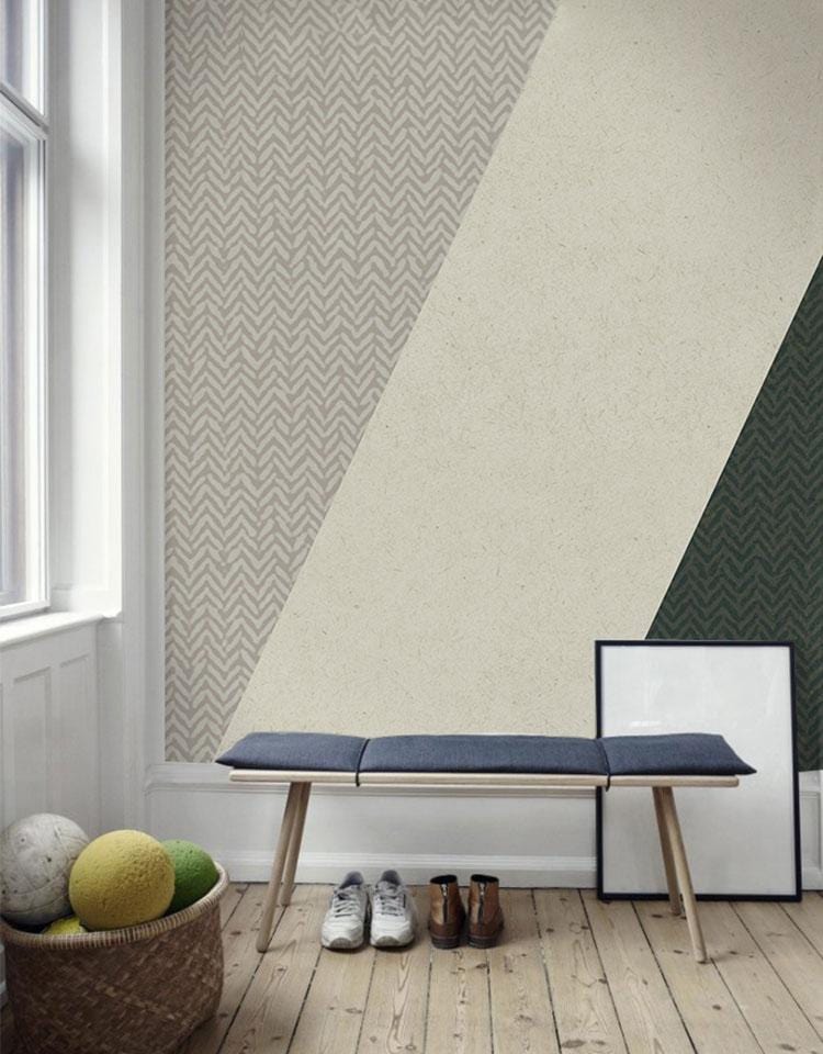 Modern geometric wallpaper with green, grey triangles in living room; wooden floor, blue bench, window.