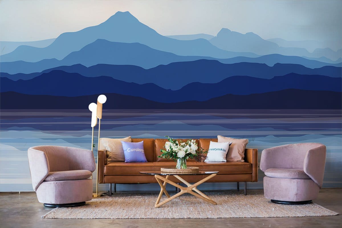 Serene Blue Mountain mural wallpaper in living room features tan sofa, pink armchairs, and modern lamp.