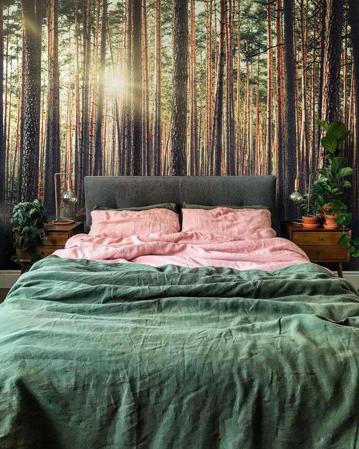 Sunlit Forest Mist mural, grey bed, lush green duvet, wooden nightstands, bedroom decor.
