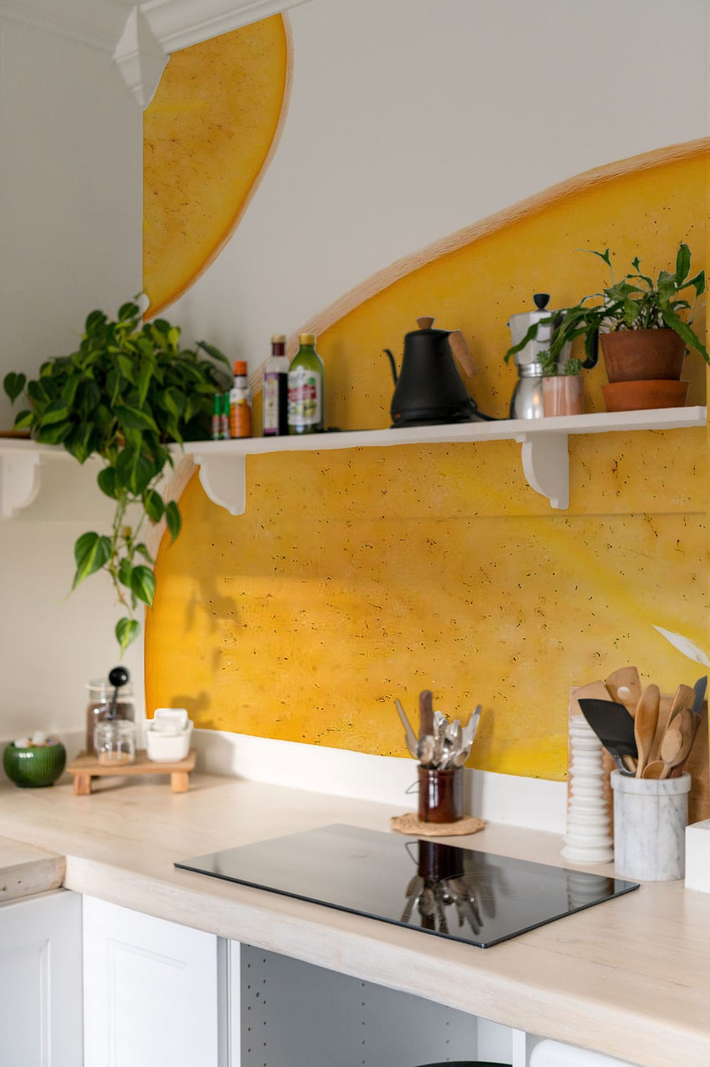 Golden Persimmon Slice wallpaper in kitchen with white shelves, modern hob, light wooden countertops.
