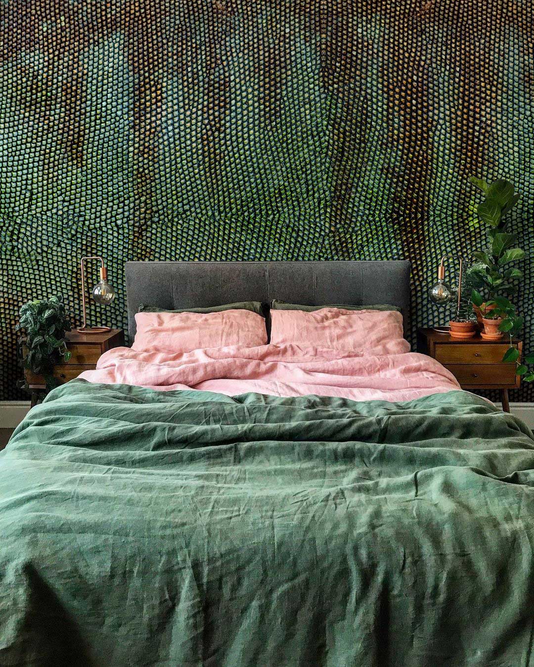 Rustic green textured wallpaper in cosy bedroom, grey upholstered headboard, pink bedding, wooden side tables.