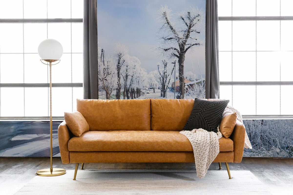 Frosty Winter Wonderland mural wallpaper with tan leather sofa, globe lamp, in modern living room setting.