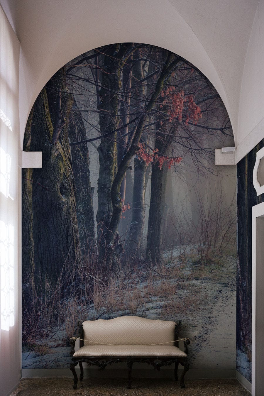 Arched Winter Forest Path mural with bench, grey serene misty landscape wallpaper in hallway.