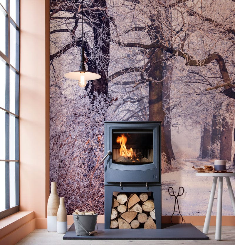 Winter Woodland Frosted mural wallpaper; stove; glass windows; wooden flooring; serene interior setting.