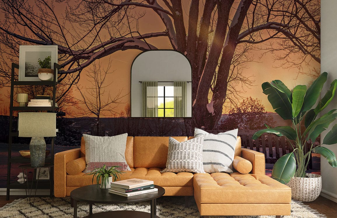 Serene Winter Sunset Mural Wallpaper with tan sofa, round mirror, dark wood flooring, and plant decor.