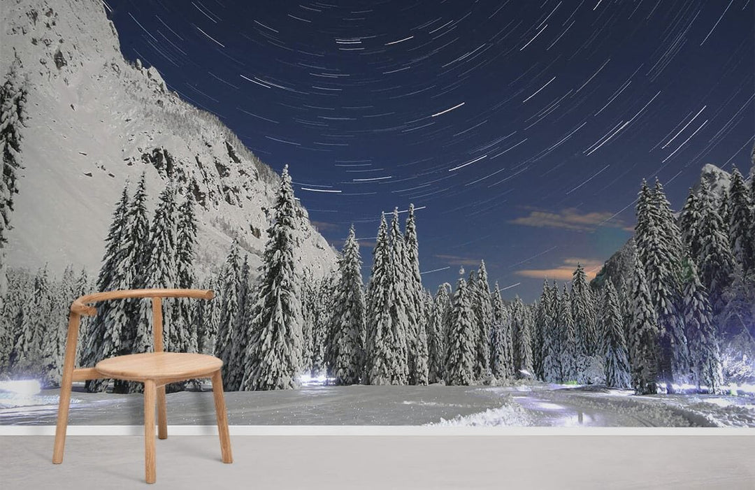 Snowy forest mural wallpaper in minimalist room with wooden chair and light flooring, night sky design.