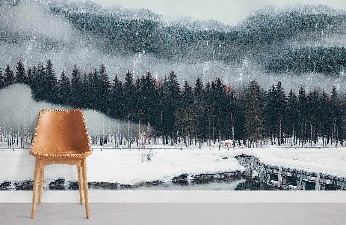Tranquil winter forest mural wallpaper in soft greys, leather chair, minimalist room with light flooring.