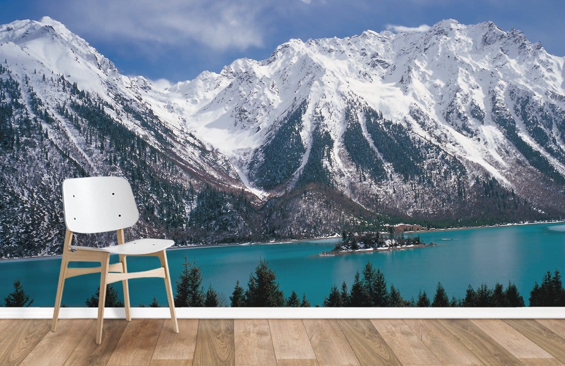 Majestic Snow-Capped Mountain Mural Wallpaper, turquoise lake, white chair, wooden flooring, serene room ambiance.