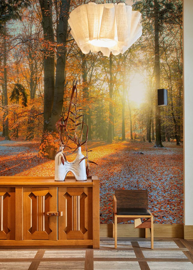 Enchanting Autumn Sunrise Forest Wallpaper in living room with wooden sideboard, chair, and soft lighting.