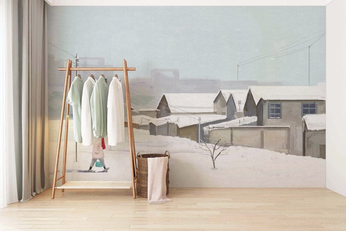 Winter Village Scene Mural Wallpaper in living room, pastel snowy landscape, wooden flooring, clothes rack.