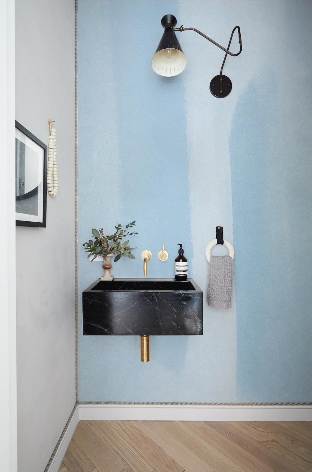 Serene Sky Blue Minimalist Wallpaper in bathroom with marble sink, light wood flooring, and modern lighting.