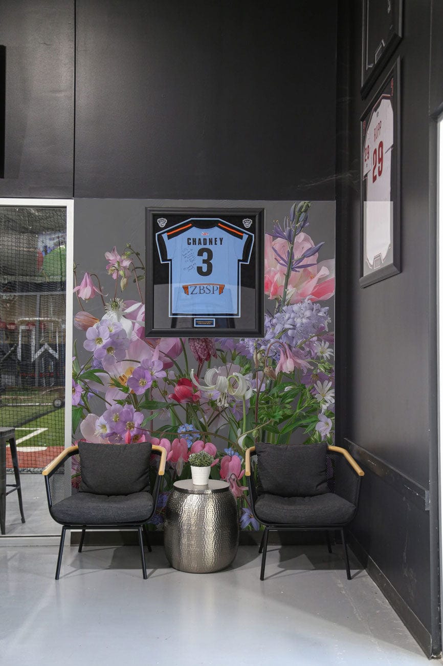 Vintage Pastel Floral Wallpaper Mural with Pink, Purple Blooms, framed sports jersey, grey modern armchairs.
