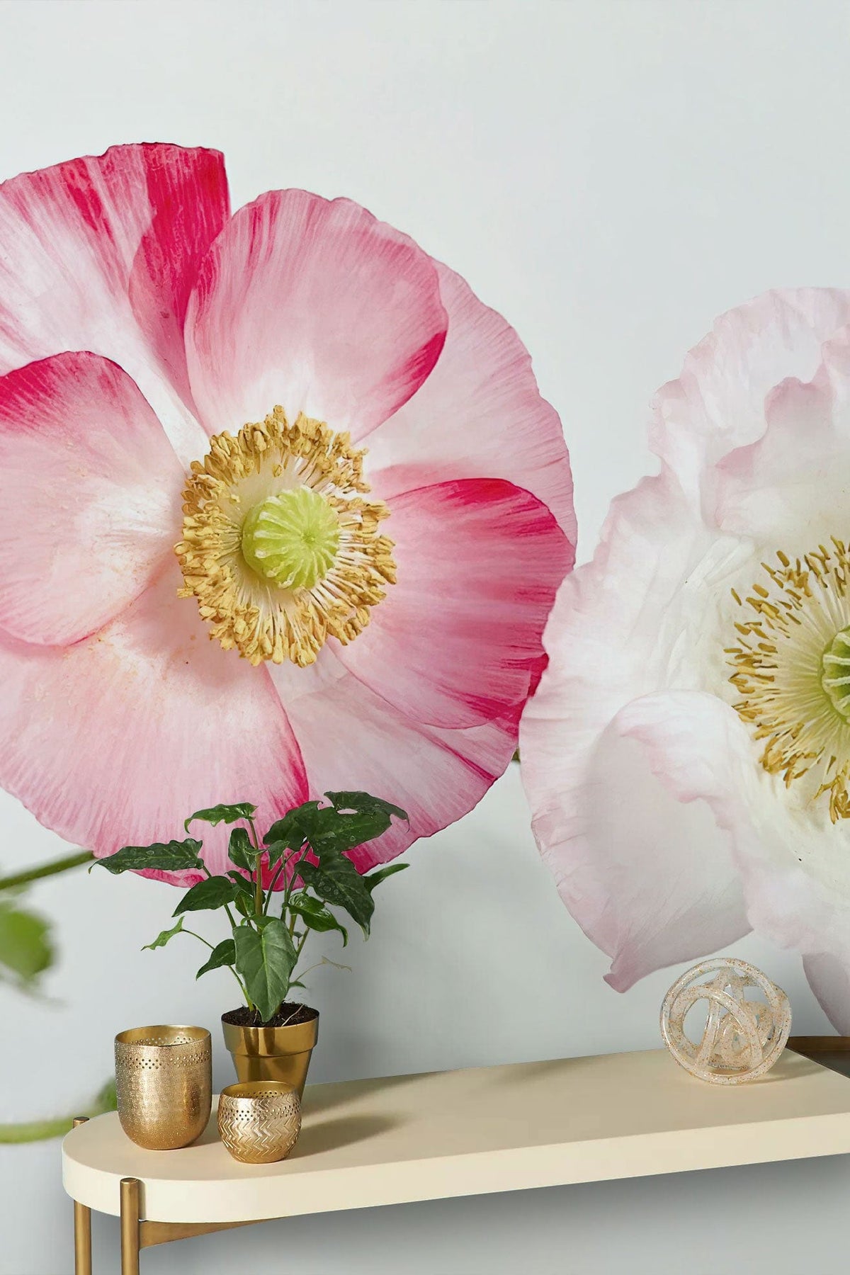 Romantic pink and white floral mural wallpaper with gold pots on a sleek tabletop.