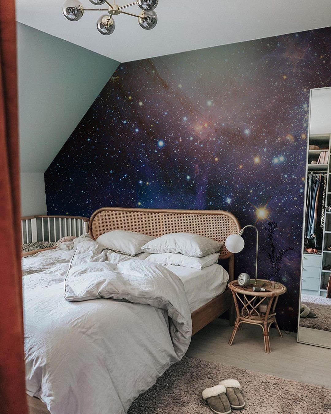 Bedroom with Celestial Galaxy Nebula Mural, wooden bed, light grey walls, stylish chandelier lighting.