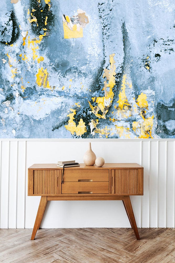 Abstract blue and gold mural wallpaper, wood sideboard, herringbone flooring in a contemporary setting.