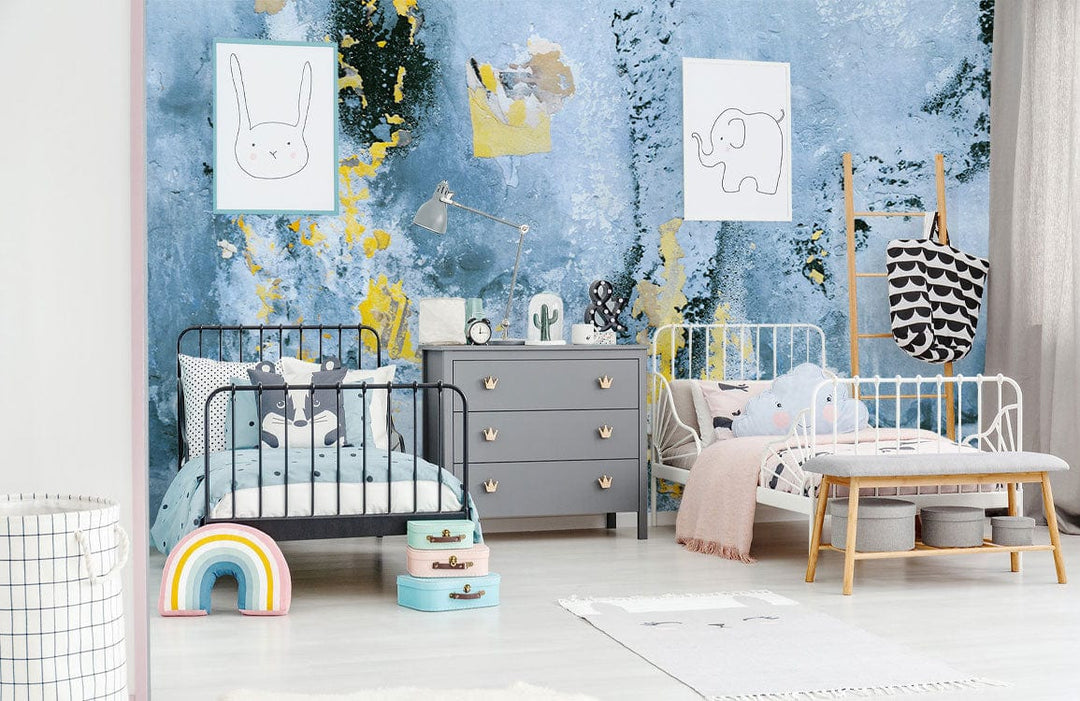 Children's room with abstract blue and gold mural wallpaper, grey dresser, colourful decor, modern beds.