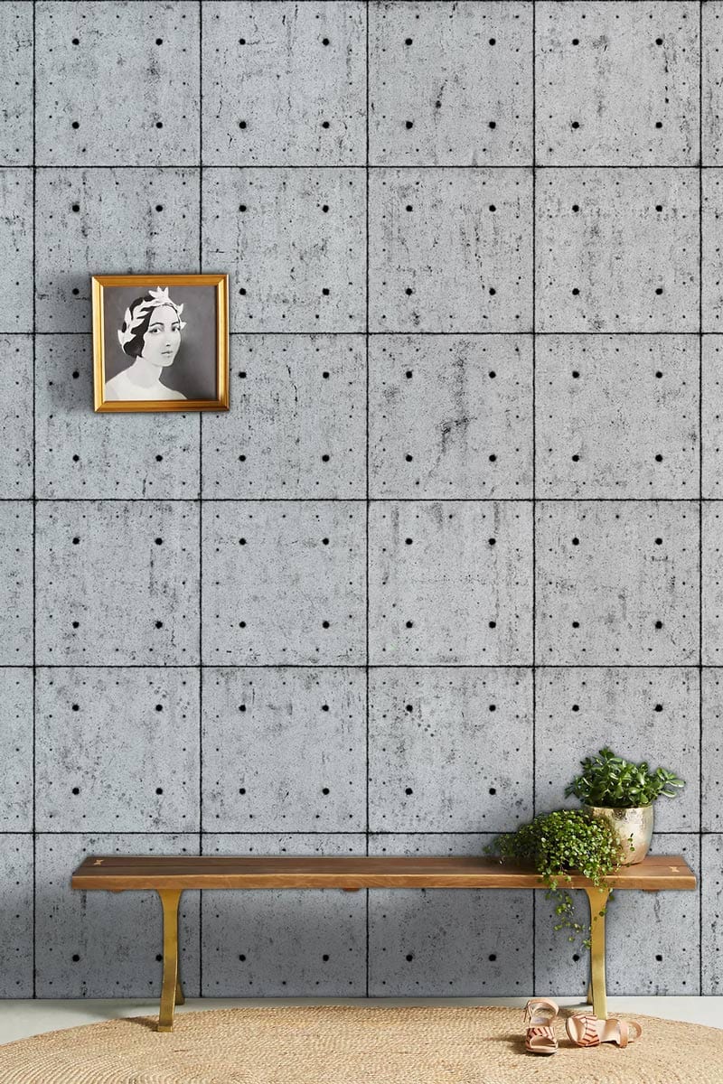 Industrial grey concrete tile effect wallpaper, wooden bench, modern artwork, textured rug in a room setting.