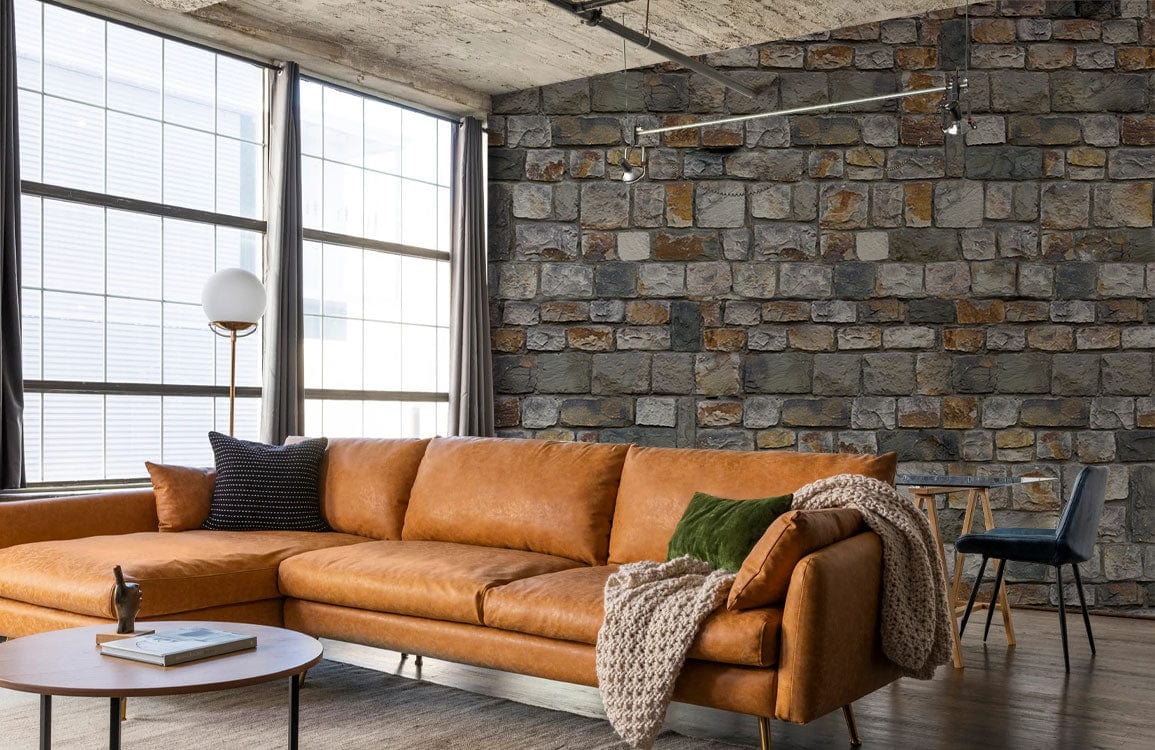Rustic Stone Brick Wallpaper in a modern living room with leather sofa, wooden flooring, large windows.