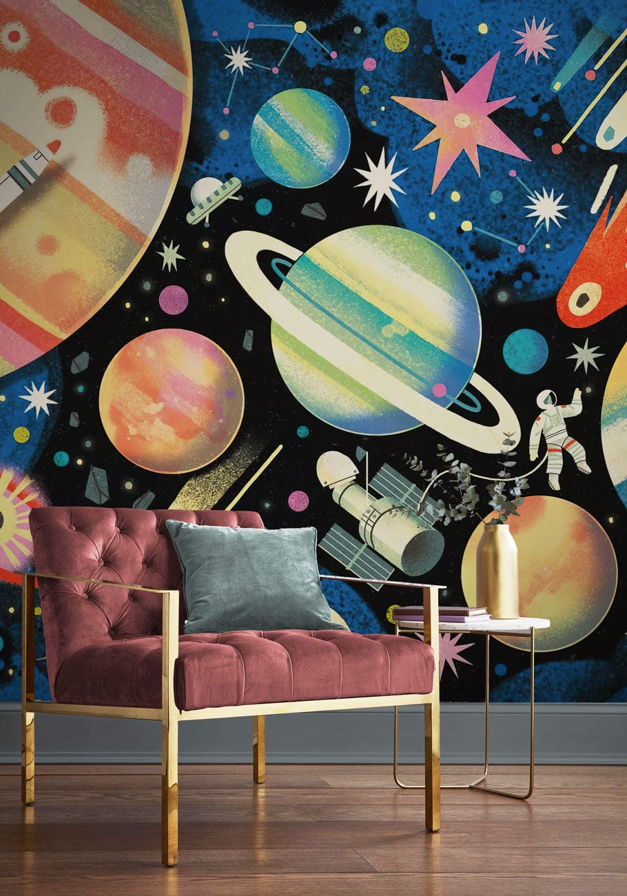Vibrant space-themed wallpaper with celestial bodies; modern children's room decor featuring a red velvet chair.