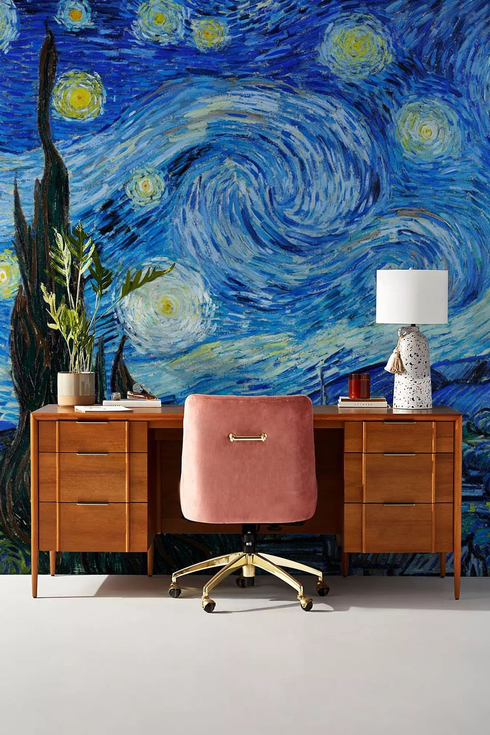 Starry Night-themed mural wallpaper, wooden desk, pink swivel chair, white lamp, modern home office decor.