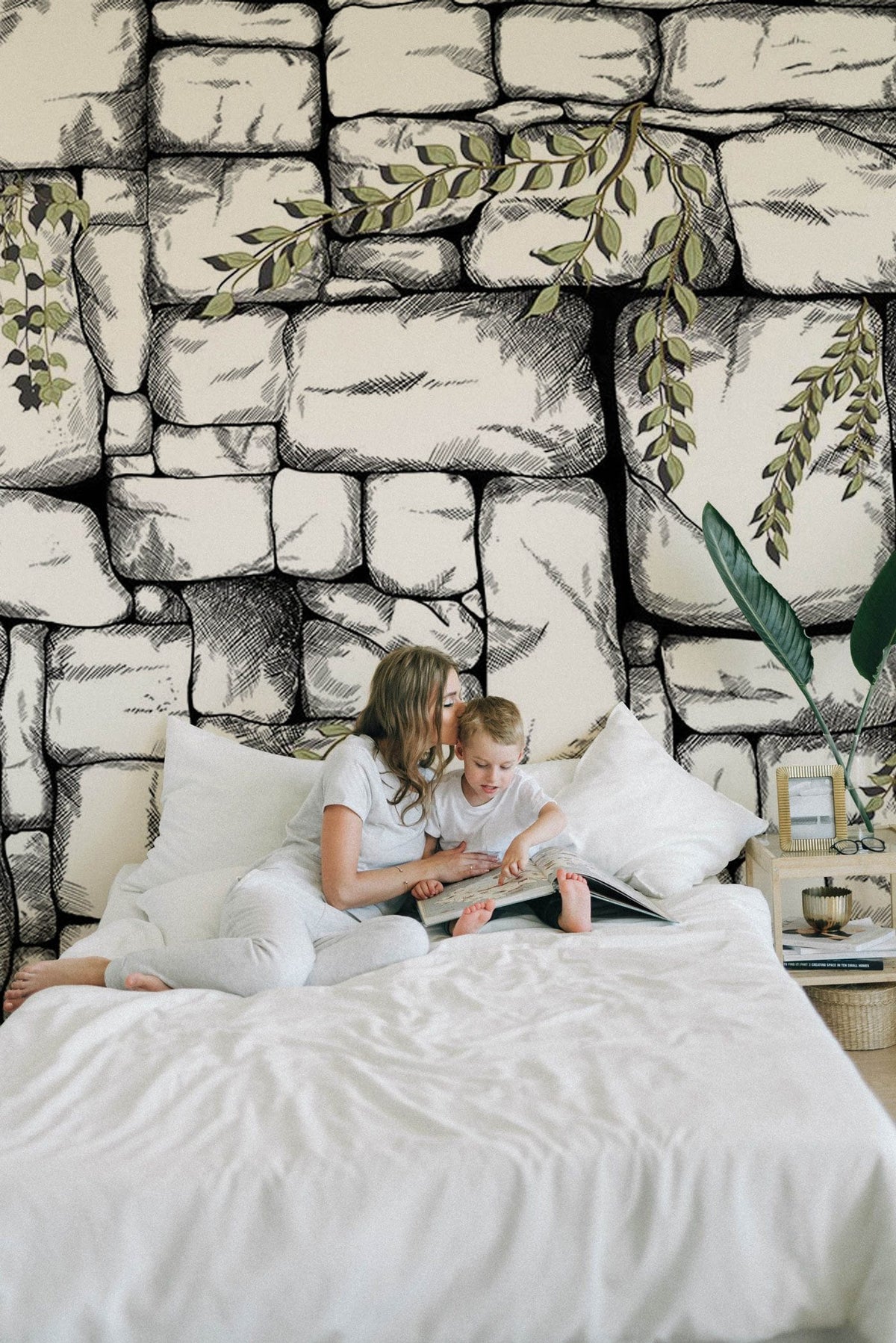 Rustic stone wall mural with greenery, black and white pattern, bedroom setting, white bedding.