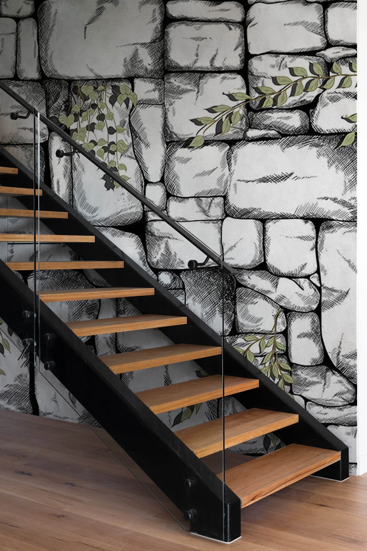Rustic stone wall mural with greenery, modern staircase, wooden flooring, stylish black railing.