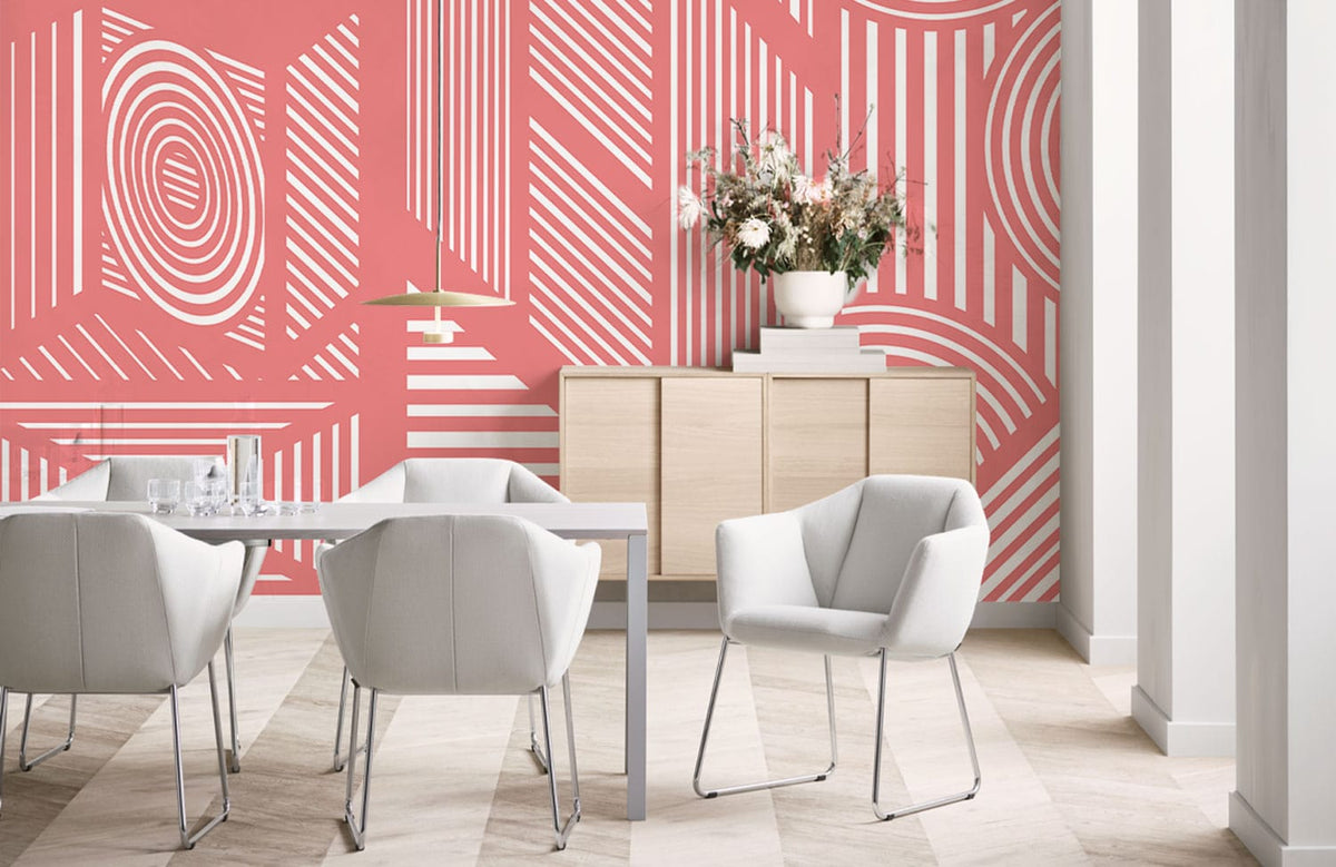 Geometric coral pink retro wallpaper in chic dining room, white chairs, light wood flooring, decorative cabinet.