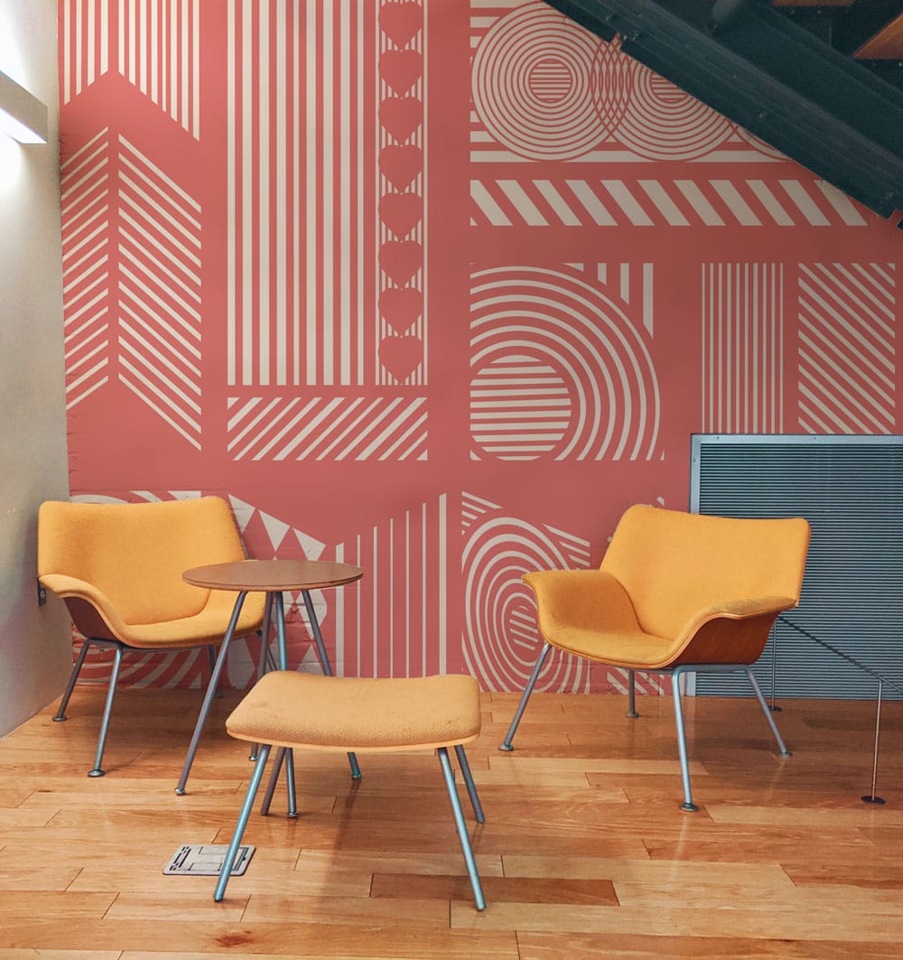 Geometric Coral Pink Retro Abstract Wallpaper, modern chairs, wooden floor in contemporary room setting.