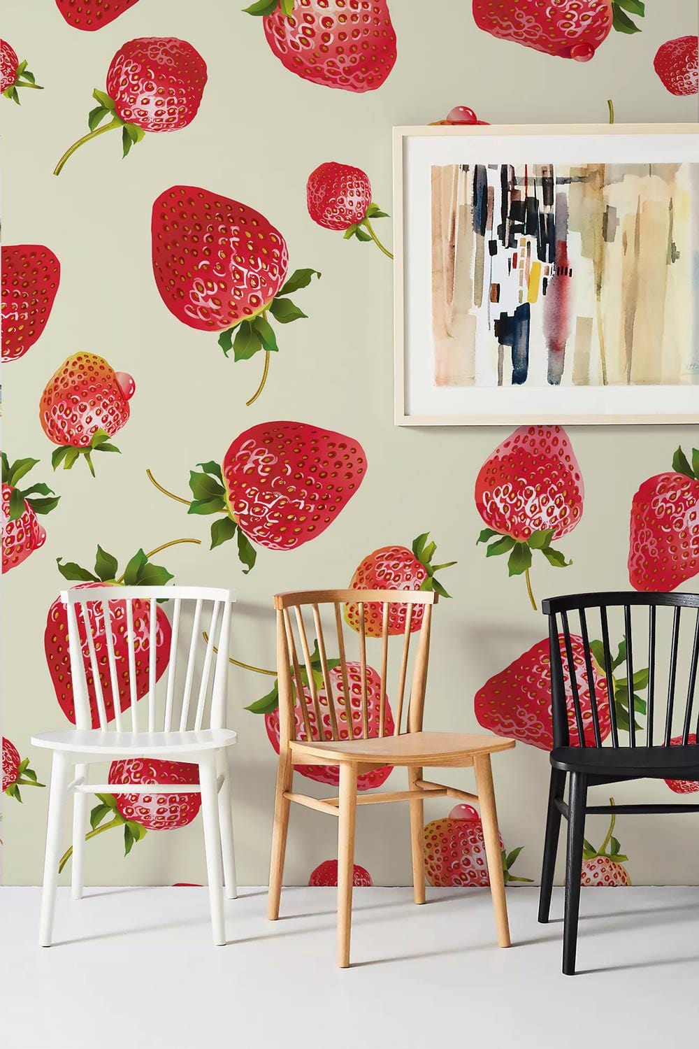 Strawberry Fields Delight wallpaper with red strawberries, white floor, and three coloured chairs in modern room.