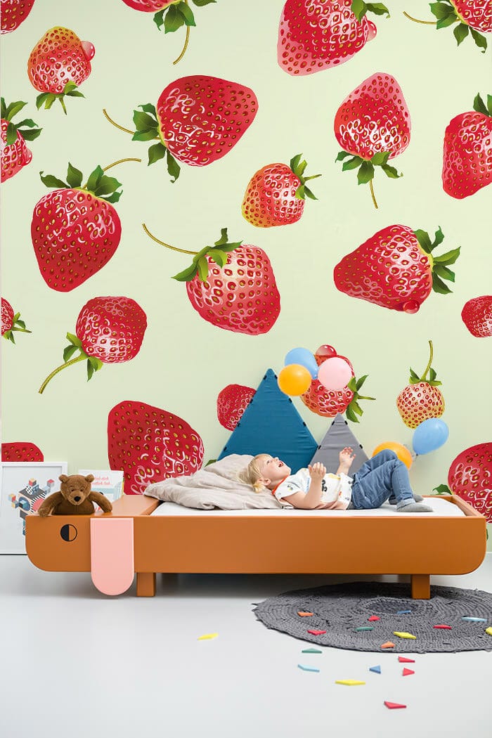 Strawberry-patterned wallpaper, vibrant reds and greens, modern children's room with brown bed and playful decor.