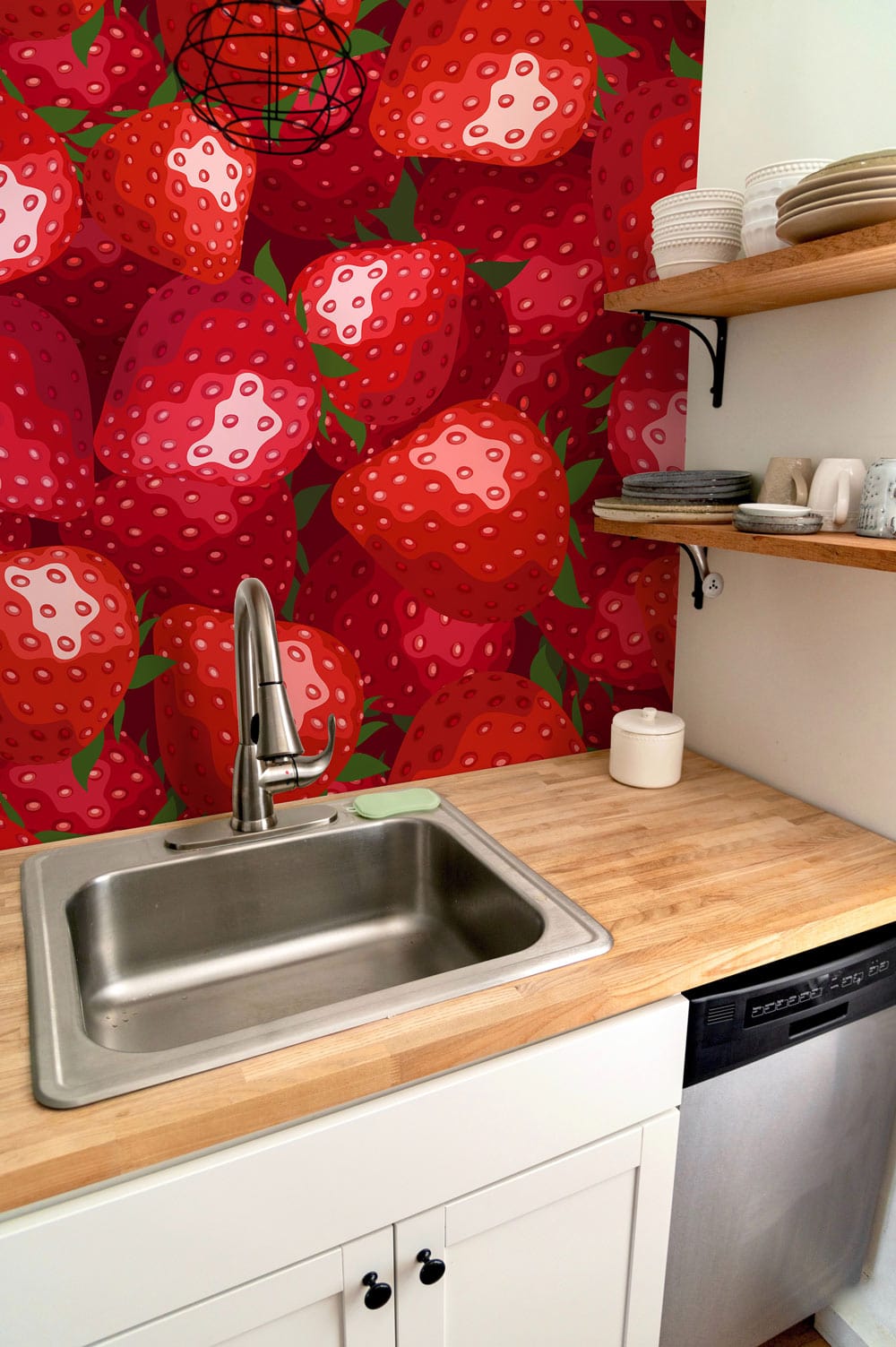 Vibrant red strawberry wallpaper in retro kitchen setting, with wooden shelves and modern silver sink.
