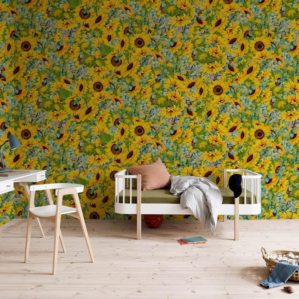 Vibrant sunflower wallpaper in yellow and green, light wood flooring, white desk, modern chair.