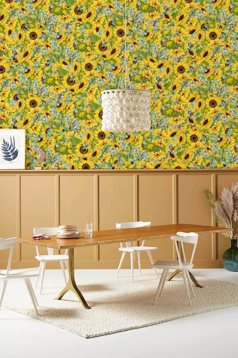 Vibrant Sunflower wallpaper, dining room setting, wooden table, white chairs, beige panelling, light carpet.