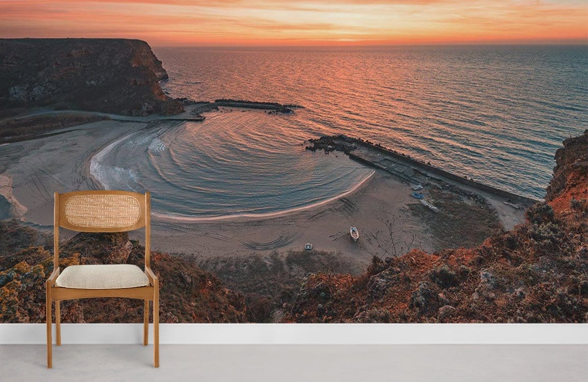 Sunset Coastal Landscape Mural Wallpaper in warm tones, featuring a wooden chair on grey flooring.