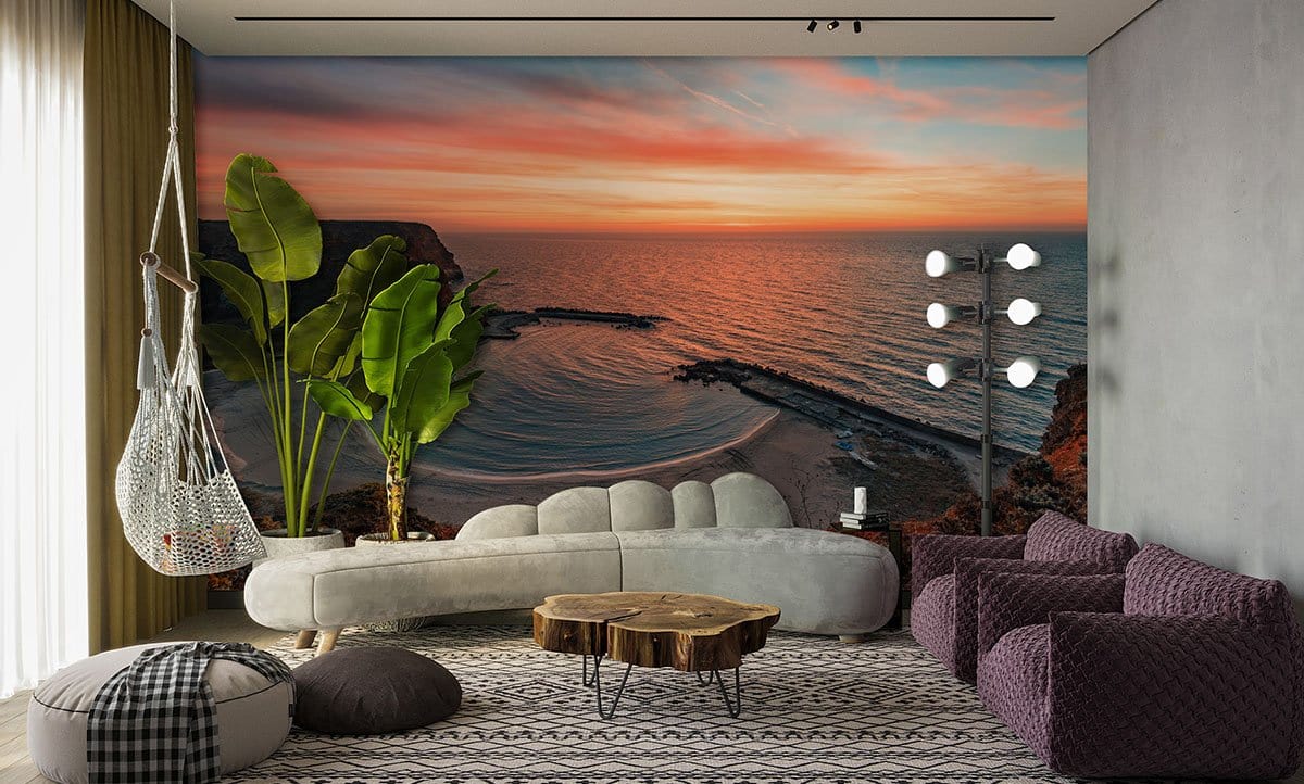Sunset Coastal Landscape Mural in earthy tones, modern grey sofa, patterned rug, vibrant green plant.