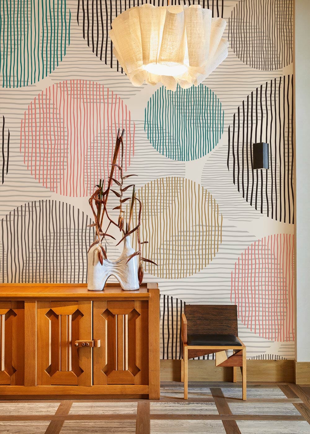 Contemporary Pastel Geometric Circles Wallpaper in modern room with wooden cabinet, unique chair, pendant light.