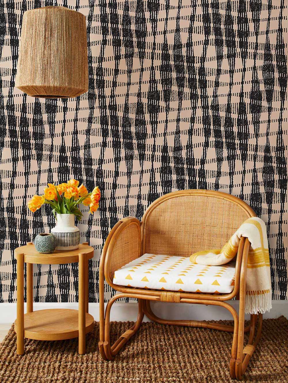 Alt text: Modern black and beige geometric wallpaper with rattan chair, wicker lamp, and wooden side table.