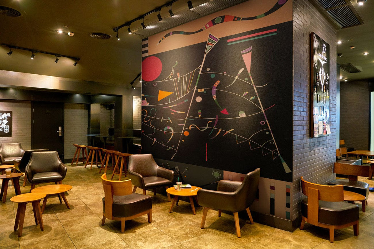 Abstract geometric art wallpaper in modern cafe setting, featuring leather chairs, wooden tables, tiled flooring.